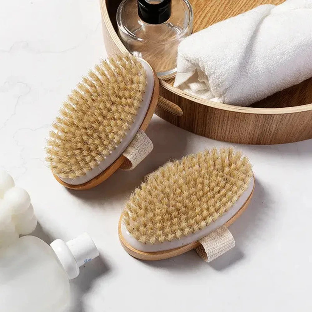 Two of the Dry Skin Brushes, the top of one is resting on a wooden basket. 