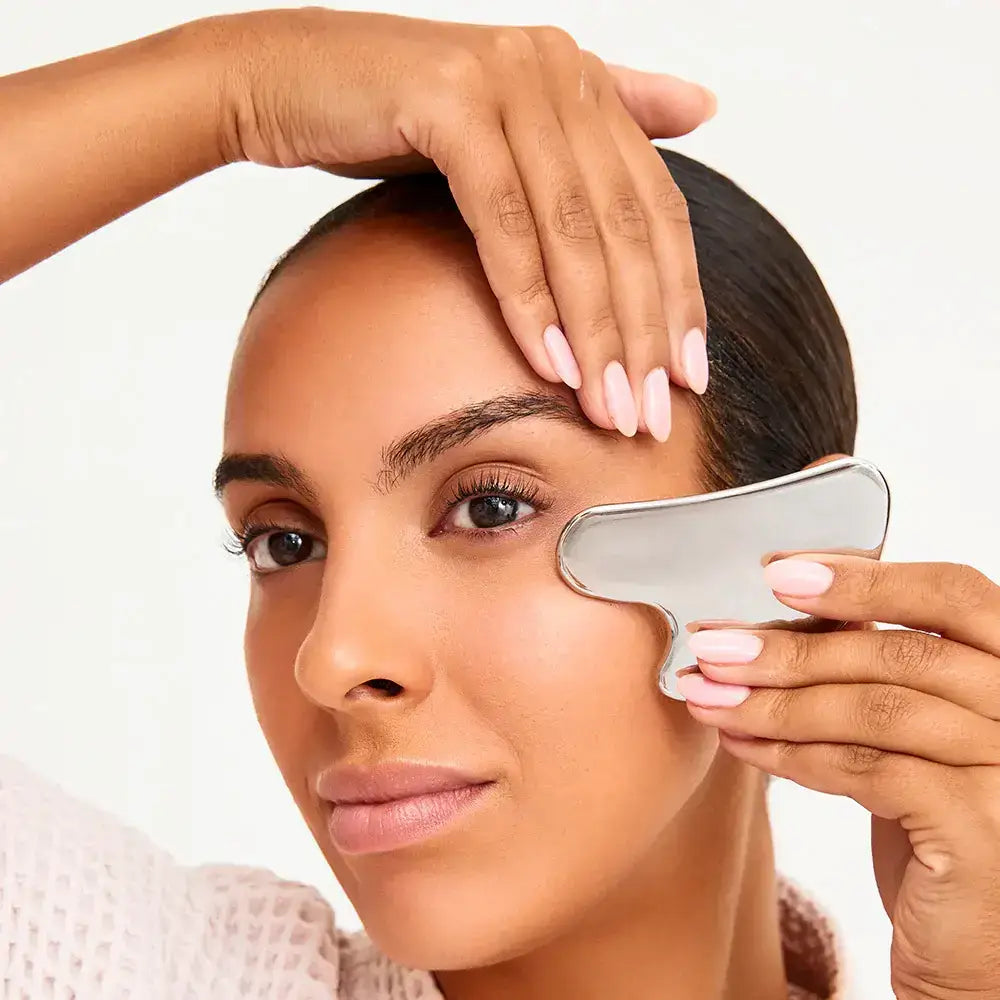 A Model using the Gua Sha Stainless Steel on her upper left cheek